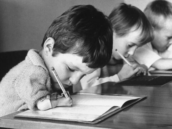 b/w photo of children with thalidomide induced disabilities writing in books