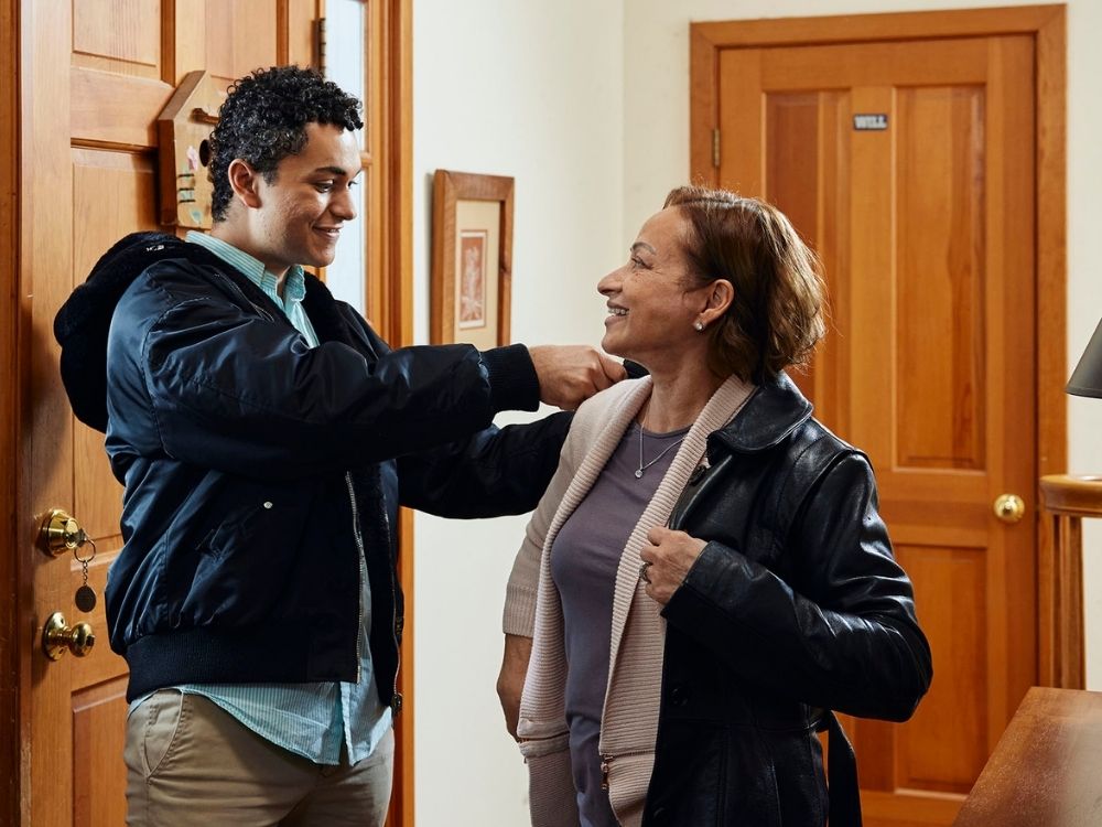 son helping mother put on coat